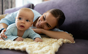 A parent lies on the ground with their baby
