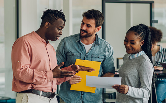 Three colleagues look at a document and have a discussion
