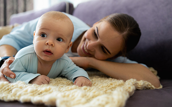 A parent cuddles with their child on a couch and smiles.