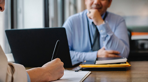 Two people writing notes during a meeting
