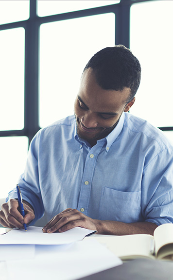 A person signs a piece of paper in a bright office