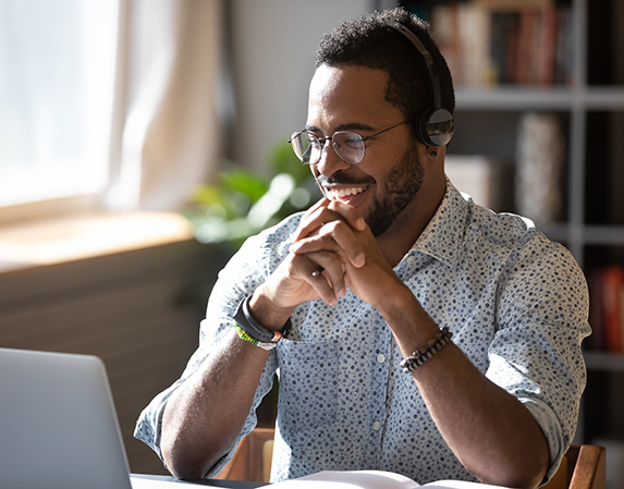 An employee wearing headphones takes a video call on their laptop