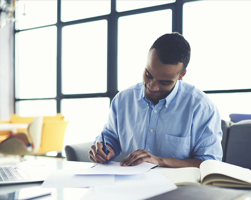 A person signs a piece of paper in a bright office